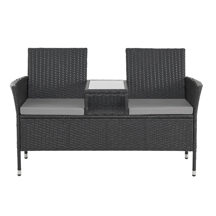 Frontalansicht einer zweisitzigen Gartenbank aus schwarzem Rattan mit zwei grauen Sitzkissen und integriertem Tisch mit Glasplatte in der Mitte