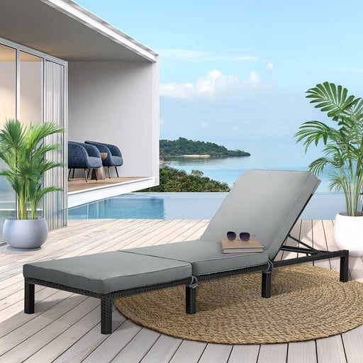 schwarze Polyrattan Gartenliege mit grauer Polsterauflage auf einer sonnigen Terrasse mit Pool