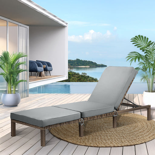 braune Polyrattan Gartenliege mit grauer Polsterauflage auf einer sonnigen Terrasse mit Pool