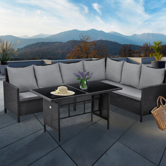 Eckige Gartenlounge mit grauen Kissen und schwarzem Tisch auf Terrasse mit Bergblick, dekoriert mit Vase und Strohhut