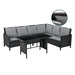 Schwarze Rattan-Ecklounge mit grauen Kissen und Tisch mit Glasplatte