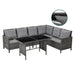 Eck-Gartenlounge aus grauem Polyrattan mit grauen Sitz- und Rückenkissen und einem rechteckigen Tisch mit schwarzer Glasplatte