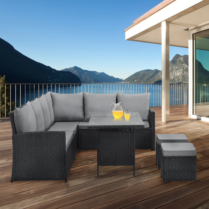 Outdoor-Sitzgruppe aus grauem Polyrattan auf Holzterrasse mit Glasplatte-Tisch, ideal für Balkon, Garten oder Seeblick-Terrasse.