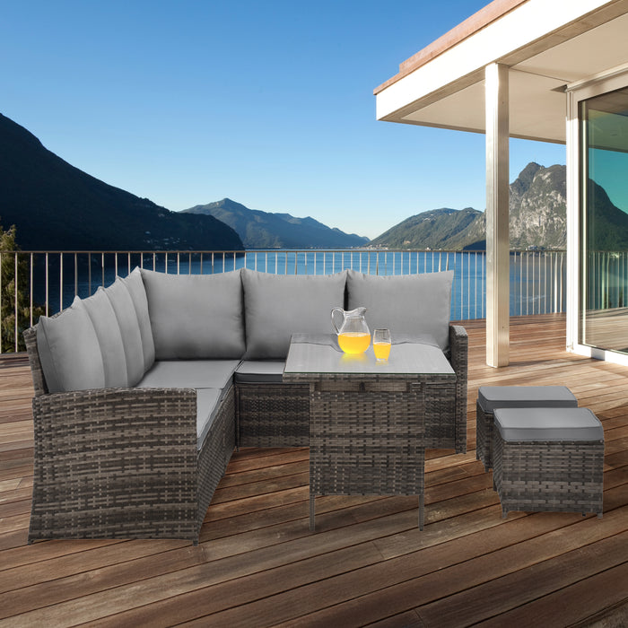 Polyrattan-Lounge-Set mit Tisch und Hockern auf moderner Terrasse mit Panorama-Ausblick auf See und Berge.