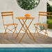 Kleines Metall-Bistro-Set mit rundem Tisch und zwei Klappstühlen in orange steht an einem Pool
