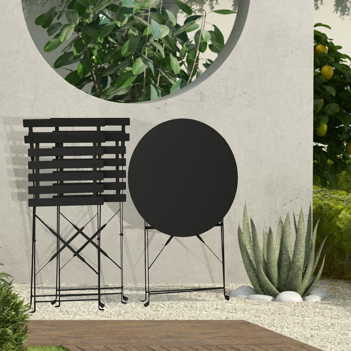 Kleines Metall-Bistro-Set mit rundem Tisch und zwei Klappstühlen in schwarz steht zusammengeklappt auf einer Terrasse