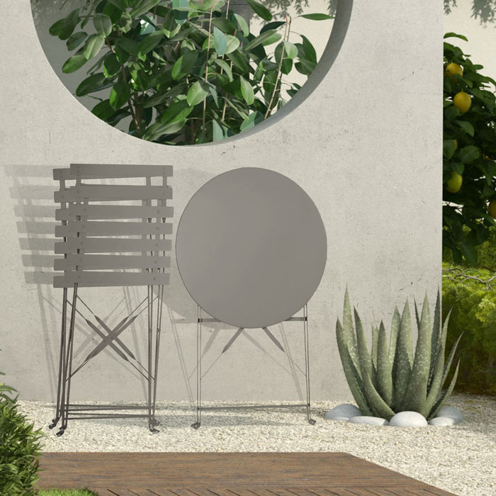 Kleines Metall-Bistro-Set mit rundem Tisch und zwei Klappstühlen in taupe steht zusammengeklappt auf einer Terrasse