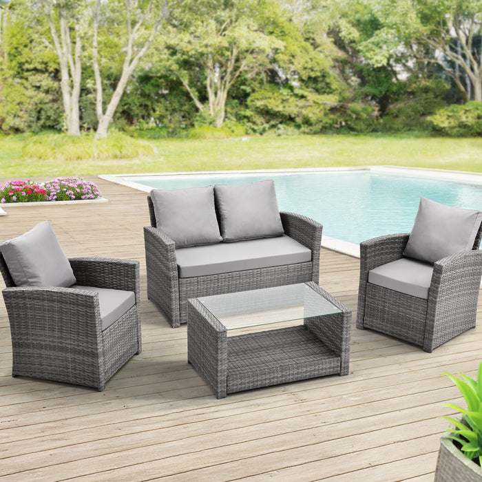 Gartenmöbel-Set aus schwarzem Polyrattan mit zwei Sesseln, einem Sofa und einem Glastisch mit Ablage auf einer Terrasse mit Pool im Hintergrund