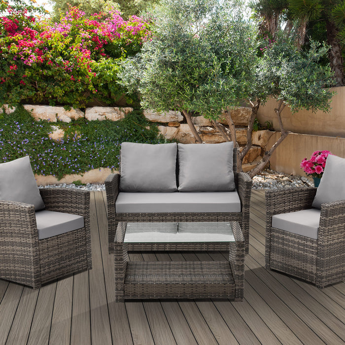 Gartenmöbel-Set aus braunem Polyrattan mit zwei Sesseln, einem Sofa und einem Glastisch mit Ablage auf einer Terrasse
