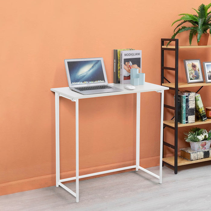 Kleiner weißer Schreibtisch mit Laptop, Büchern und Stiftbecher vor orangefarbener Wand, neben schwarzem Regal mit Pflanzen und Bildern