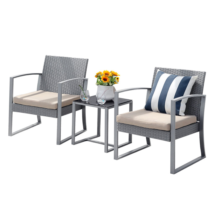Zweisitzige graue Rattan-Gartenmöbel mit beigen Sitzkissen, kleinem schwarzen Tisch dazwischen mit Blumenvase und zwei Gläsern, ein Stuhl mit blau-weiß gestreiftem Kissen