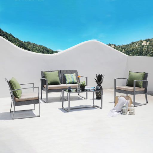 Moderner Gartenmöbel-Set mit zwei Sesseln, einer Bank und einem Glastisch auf weißem Boden vor weißer Wand und blauem Himmel