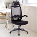 Schwarzer ergonomischer Bürostuhl mit Netzrückenlehne, verstellbarer Kopfstütze und Armlehnen in einem hellen Arbeitszimmer