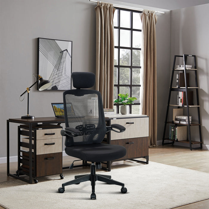 Schwarzer ergonomischer Bürostuhl mit Netzrückenlehne vor einem Schreibtisch mit Laptop und Schreibtischlampe in modernem Arbeitszimmer mit Fenster, Vorhängen und Bücherregal