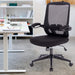 Schwarzer ergonomischer Bürostuhl mit Netzrückenlehne und Armlehnen vor einem weißen Schreibtisch mit Laptop und Notizbuch