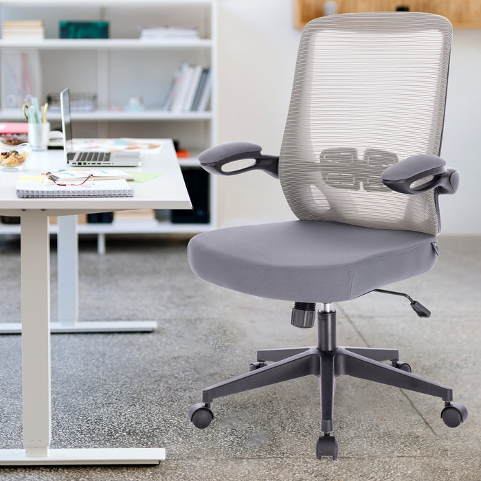 Grauer ergonomischer Bürostuhl mit Netzrückenlehne und Armlehnen vor einem weißen Schreibtisch mit Laptop und Notizbuch