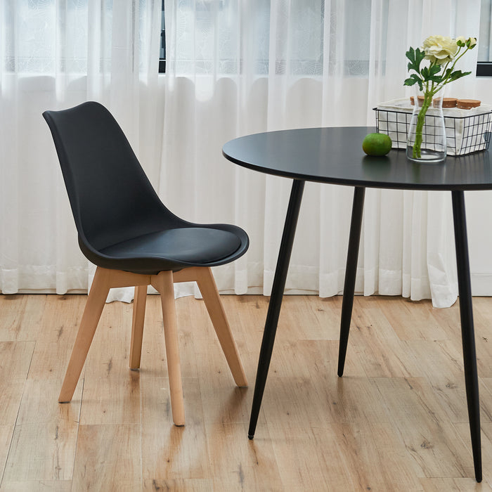 Schwarzer SVITA Mats Esszimmerstuhl mit elegantem Design neben einem schwarzen Tisch mit Vase und grünem Apfel