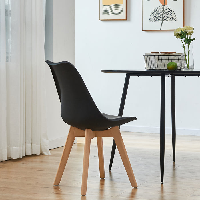 Bequemer SVITA Mats Esszimmerstuhl in Schwarz mit Holzbeinen neben rundem schwarzem Tisch mit Blumenvase und Obst
