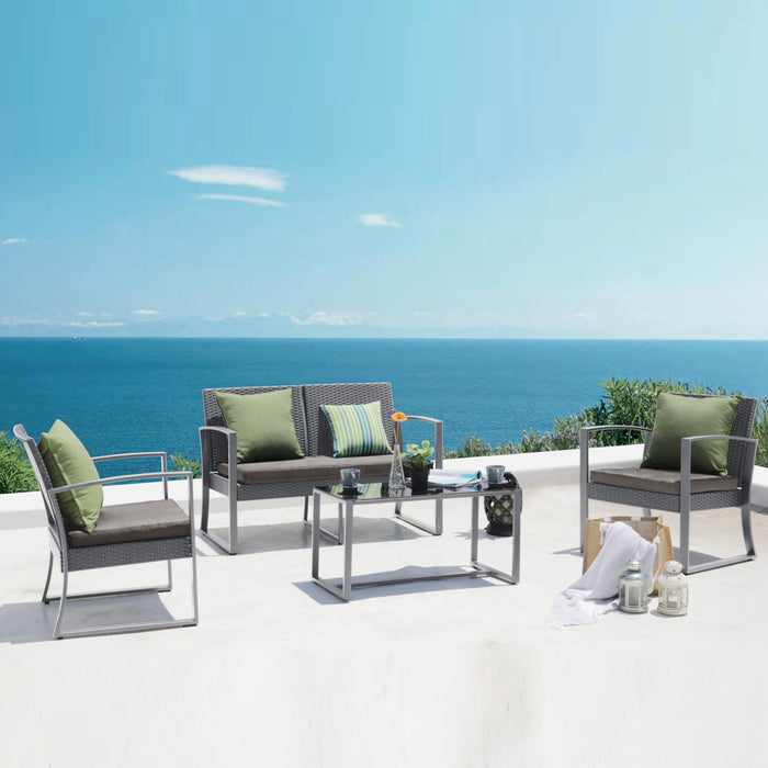 Moderner Sitzbereich mit grauen Polstersesseln und Sofa, grüne Kissen, Glastisch auf weißer Terrasse mit Meerblick