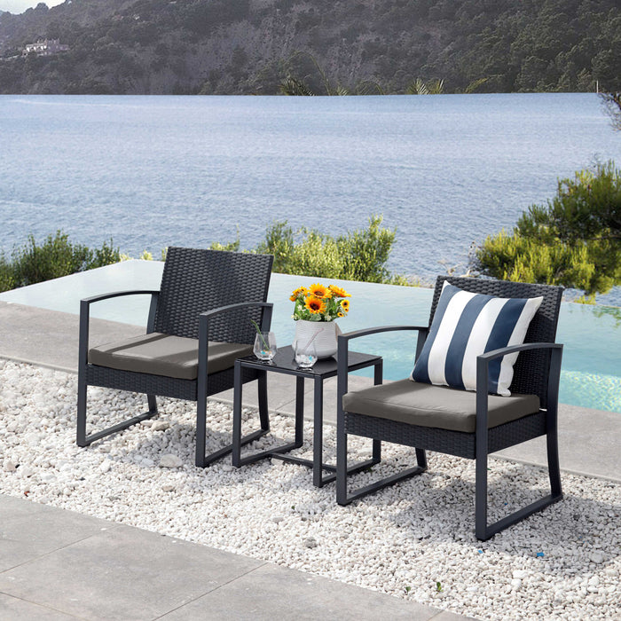 Zwei schwarze Gartenstühle mit grauen Sitzkissen und ein kleiner schwarzer Beistelltisch mit Sonnenblumen in Vase am Pool mit Blick auf See und bewaldeten Hügel