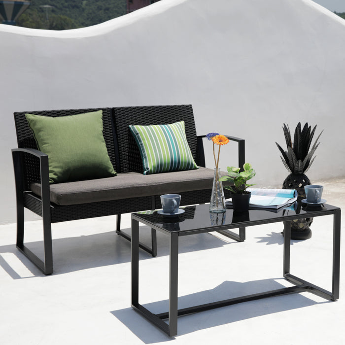 Schwarzes Garten-Sofa mit grünen Kissen und schwarzer Glastisch mit Vasen, Pflanze und Tassen auf weißem Hintergrund