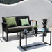 Schwarzes Garten-Sofa mit grünen Kissen und schwarzer Glastisch mit Vasen, Pflanze und Tassen auf weißem Hintergrund
