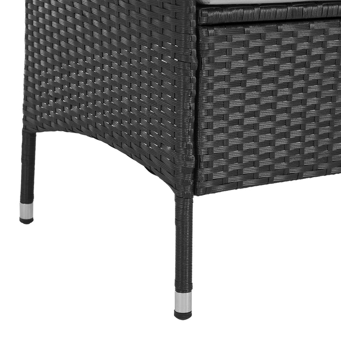 Beine einer schwarzen, geflochtenen Gartenbank aus Polyrattan mit Metallkappen am Fuß