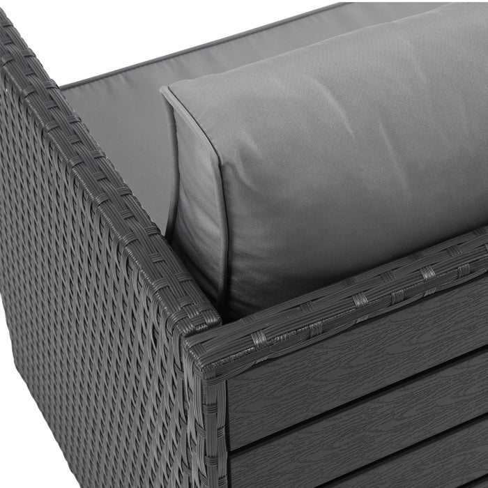 Eckdetail des schwarzen Polyrattan-Gartensofas mit grauem Kissen und schwarzer Tischplatte an der Rückseite