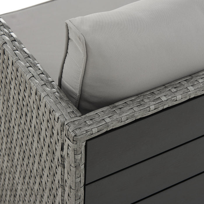 Eckdetail des grauen Polyrattan-Gartensofas mit grauem Kissen und schwarzer Tischplatte an der Rückseite