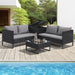 Schwarze Polyrattan Gartenlounge mit Kissenbox auf einer sonnigen Terrasse am Pool, auf dem Tisch stehen eine Flasche und Gläser