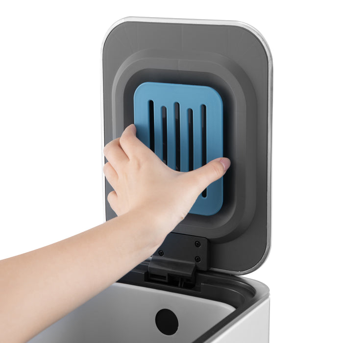 Hand öffnet silbernen Mülleimer mit schwarzem Innenraum und blauem Aktivkohlefilter im Deckel