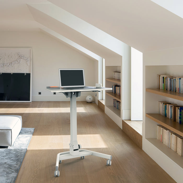 Weißes Stehpult mit Laptop und Tasse in einem hellen Raum mit Dachschräge und eingebauten Bücherregalen