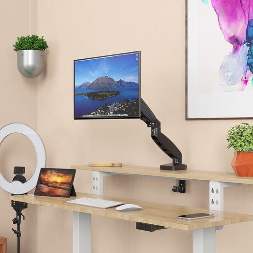 Moderner Arbeitsplatz mit zwei Holzplatten, einem an der oberen Platte befestigten Monitorarm mit Bildschirm, Tablet, Tastatur, Maus und Smartphone, umgeben von Pflanzen und einem Ringlicht