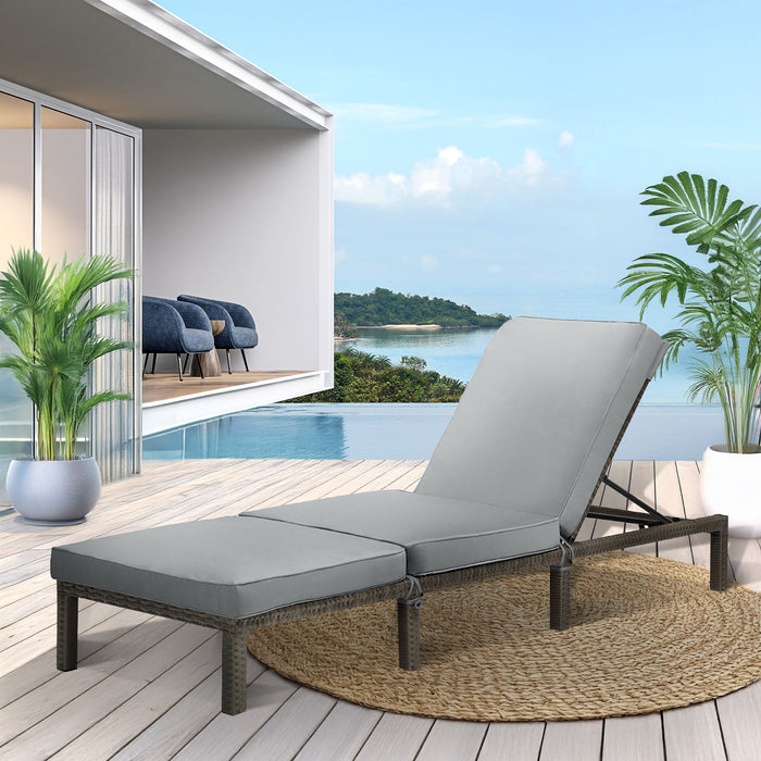 Graue Polyrattan Gartenliege mit grauer Polsterauflage auf einer sonnigen Terrasse mit Pool