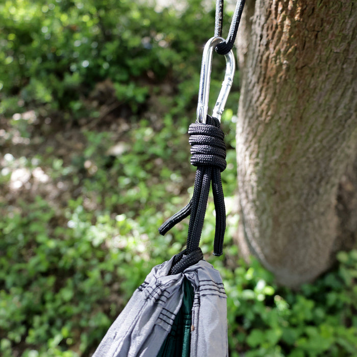 Karabinerhaken mit schwarzem Seil, an grauer Hängematte, das an einem Baum befestigt ist