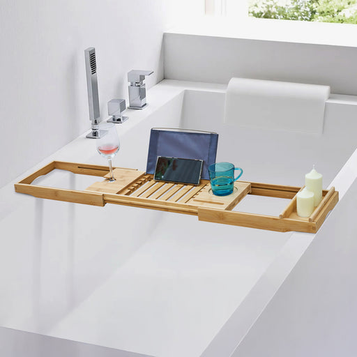 Badewannenablage aus Bambus liegt auf einer Badewanne, darauf ein Weinglas, Smartphone, eine Glastasse und zwei Kerzen