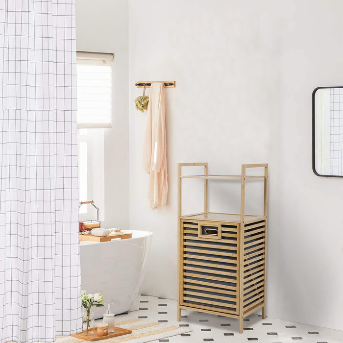 Ein Bambus Badregal mit Wäschekorb steht in einem hellen Badezimmer mit freistehender Badewanne mit weißem Duschvorhang mit Karomuster und rechteckigem Spiegel an der Wand