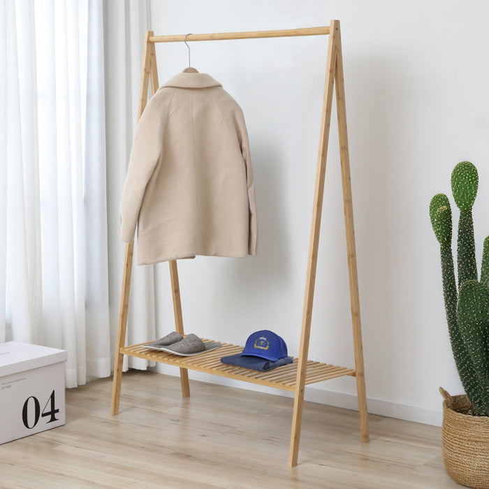 Ein beiger Mantel hängt an einem einfachen Holzkleiderständer mit einer blauen Kappe und grauen Hausschuhen auf einem Regalfach darunter