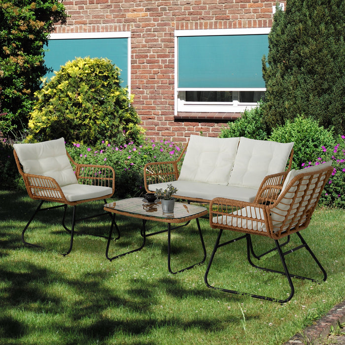 Gartenmöbel-Set mit zwei Sesseln, einem Sofa und einem Tisch mit Pflanzen auf grünem Rasen vor einem Backsteinhaus mit zwei Fenstern und grünen Markisen