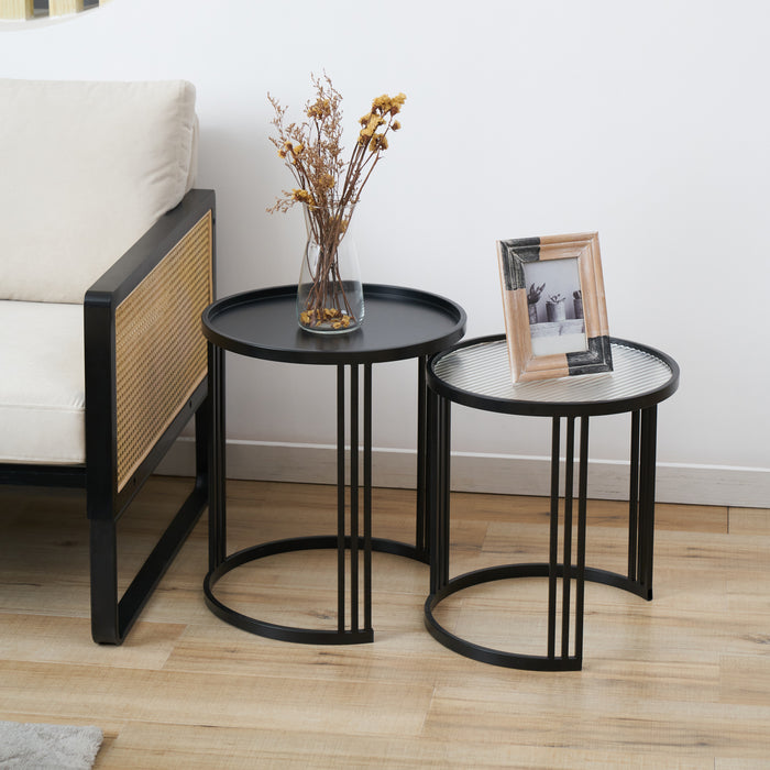 Zwei schwarze Beistelltische mit Metallgestell, einer mit glatter Platte und Vase mit getrockneten Blumen, der andere mit geriffelter Glasplatte und Bilderrahmen