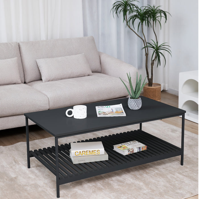 Schwarzer rechteckiger Couchtisch mit Tasse, Magazin und Pflanze, davor helles Sofa und große Zimmerpflanze