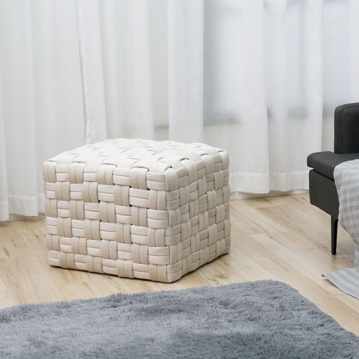 Weißer, gewebter Samt-Hocker in Würfelform auf hellem Holzboden vor weißen Vorhängen, neben grauem Sofa