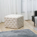 Weißer, gewebter Samt-Hocker in Würfelform auf hellem Holzboden vor weißen Vorhängen, neben grauem Sofa