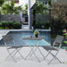 Graues, klappbares Balkon-Set mit quadratischem Tisch und zwei Stühlen aus geflochtenem Material stehen auf einer Terrasse mit Pool im Hintergrund