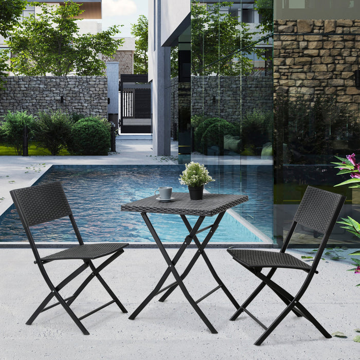 Schwarzes, klappbares Balkon-Set mit quadratischem Tisch und zwei Stühlen aus geflochtenem Material stehen auf einer Terrasse mit Pool im Hintergrund